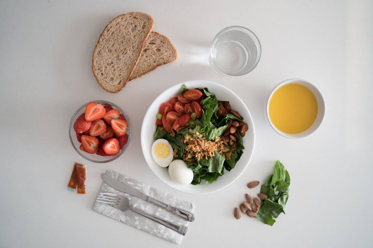 Top view of a nutritious breakfast with salad, eggs, bread, and juice, perfect for a healthy start.